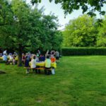 Menschen an Tischen auf einer grünen Wiese